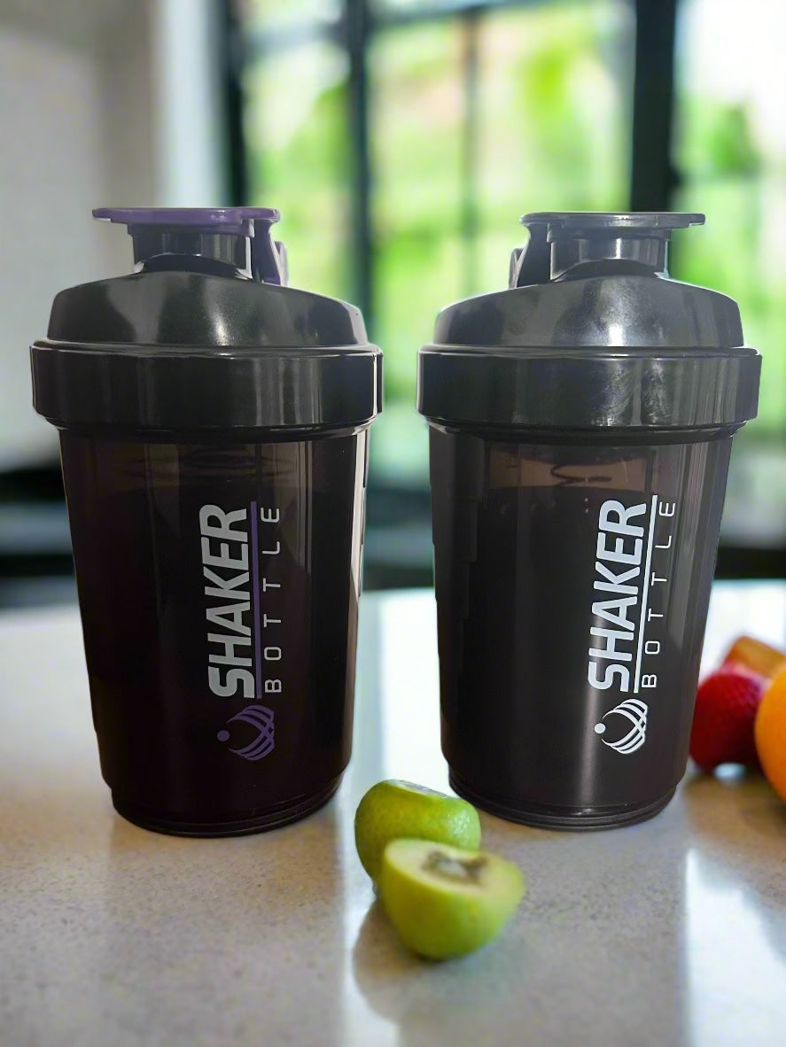 Two black shaker bottles with purple tops on a wooden surface.
